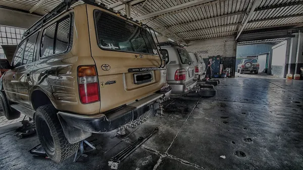 A line of Land Cruisers in the workshop, with one up on stands